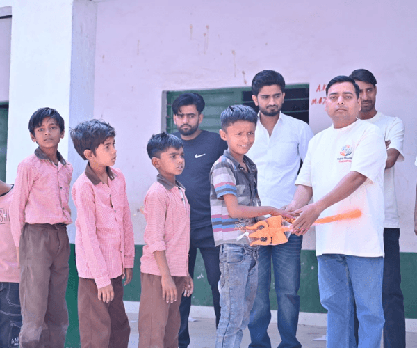 Man distributing colourful toys to young boys lined up during an NCF children's outreach event