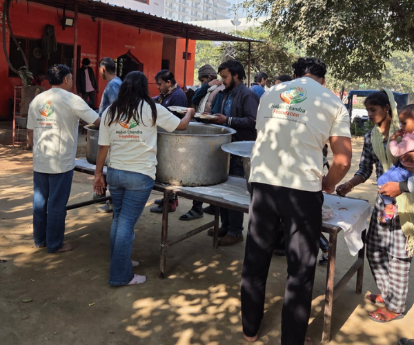 Volunteers serving food from massive cooking pots to a line of people