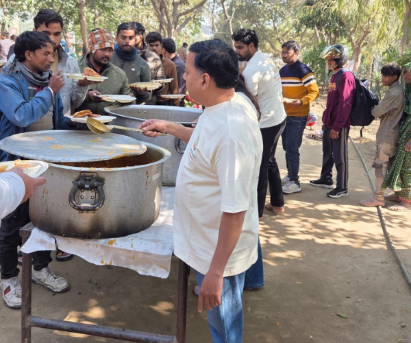 NCF founder serving hot food from a large cooking pot to a queue of beneficiaries during a community food drive